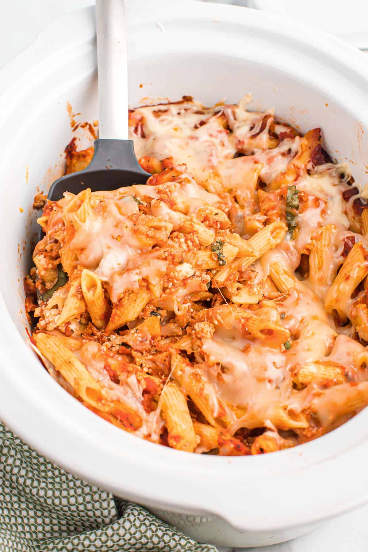 taking a scoop of baked ziti from the crock pot