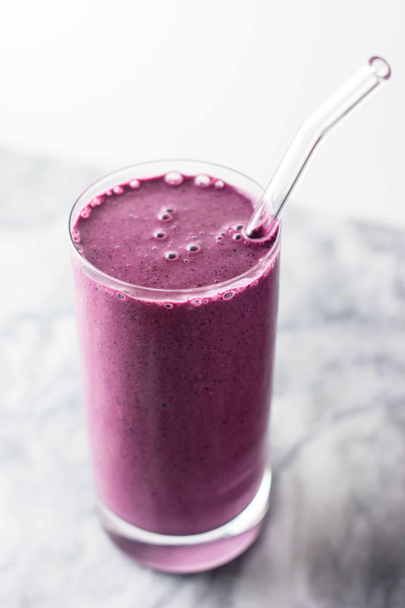 blueberry pie smoothie in a glass with a glass straw