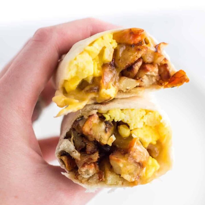 a hand holding a breakfast burrito cut open