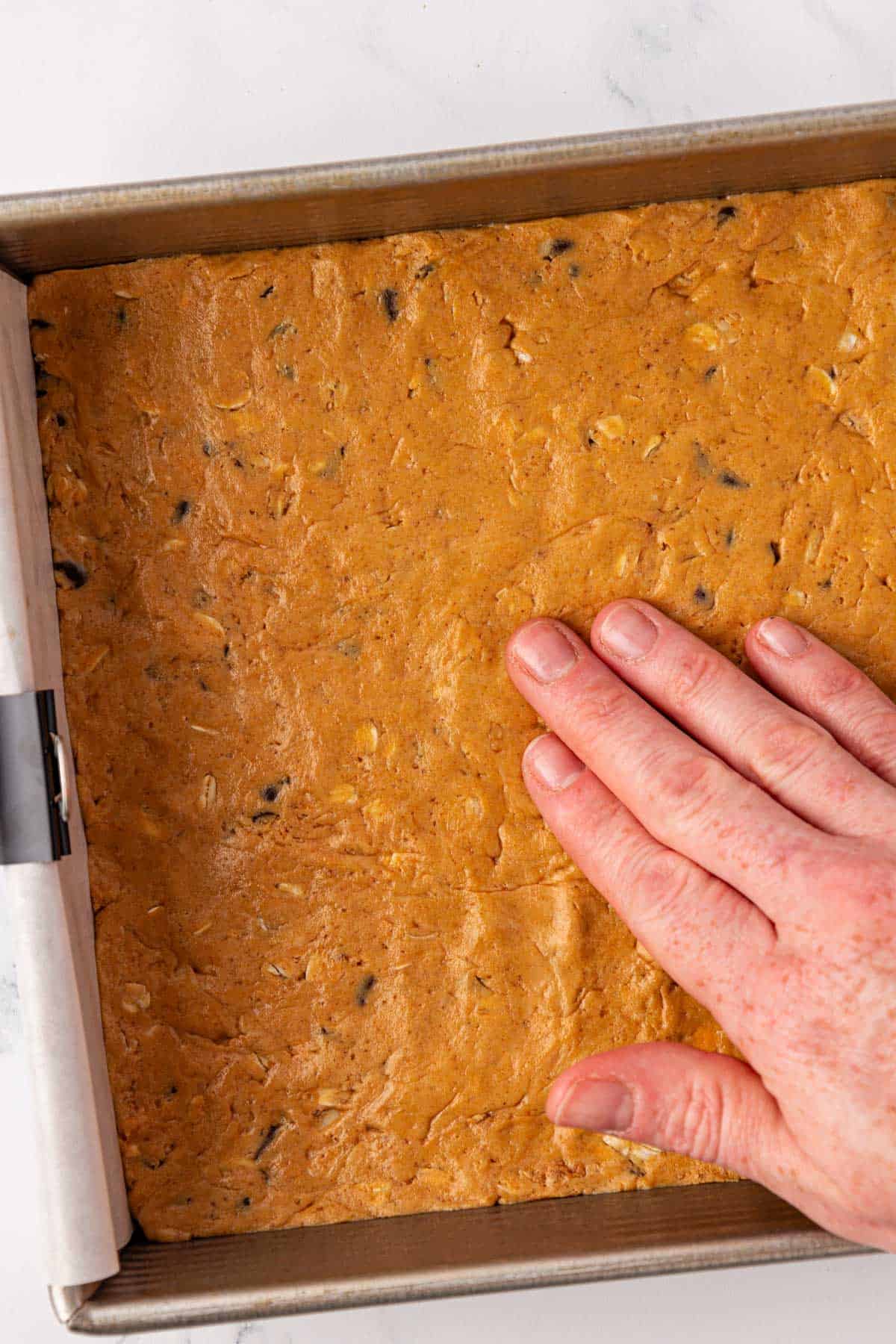 pressing the protein bar batter with a hand
