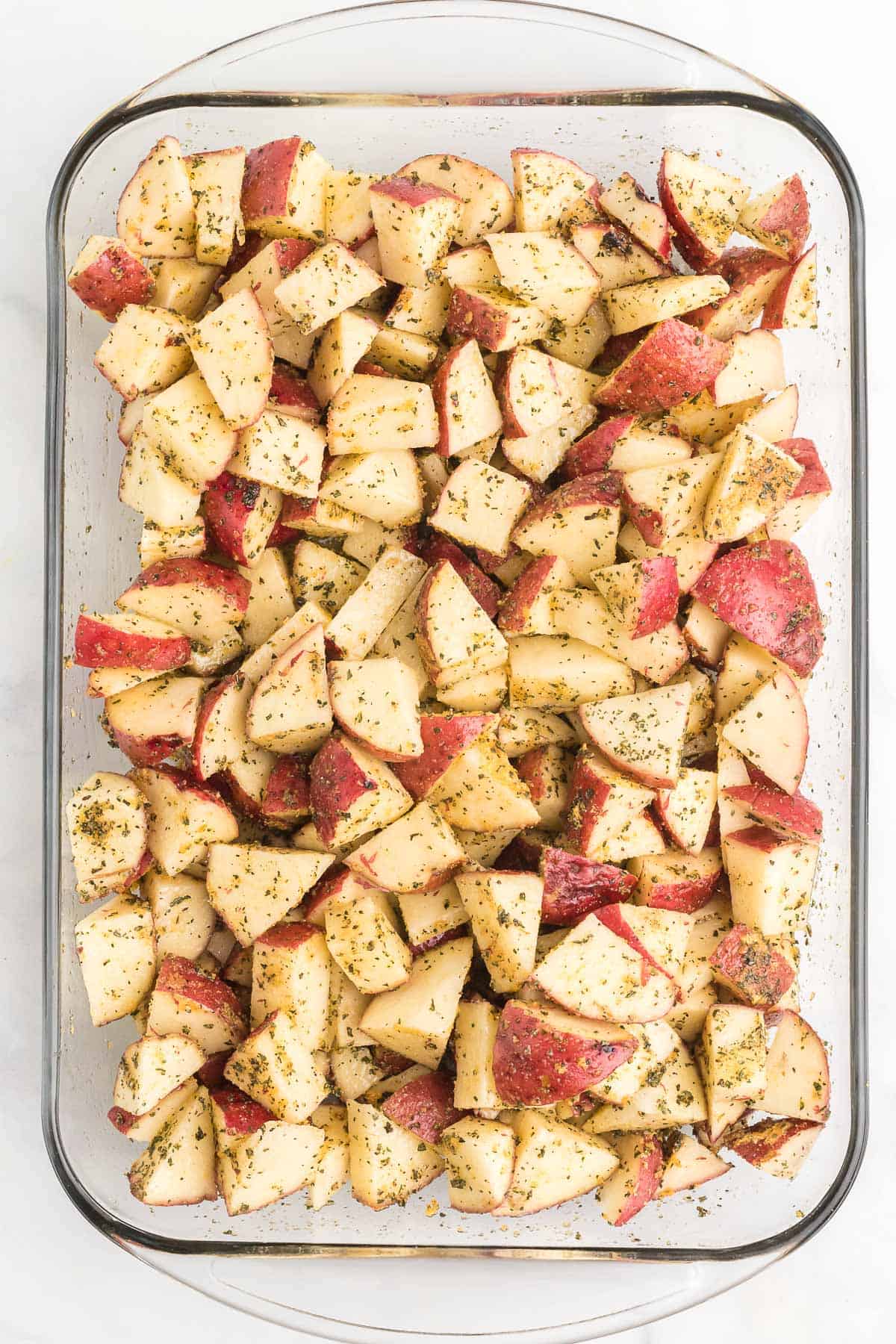 diced red potatoes mixed with spices and oil in a baking dish