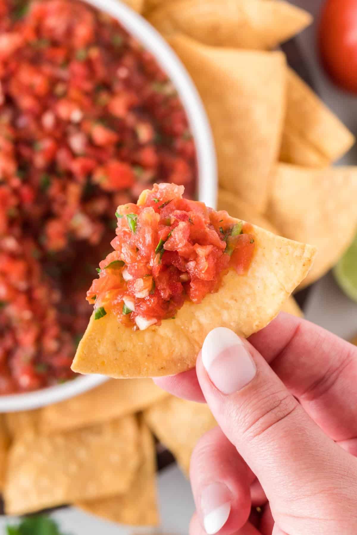 hand holding a chip with salsa
