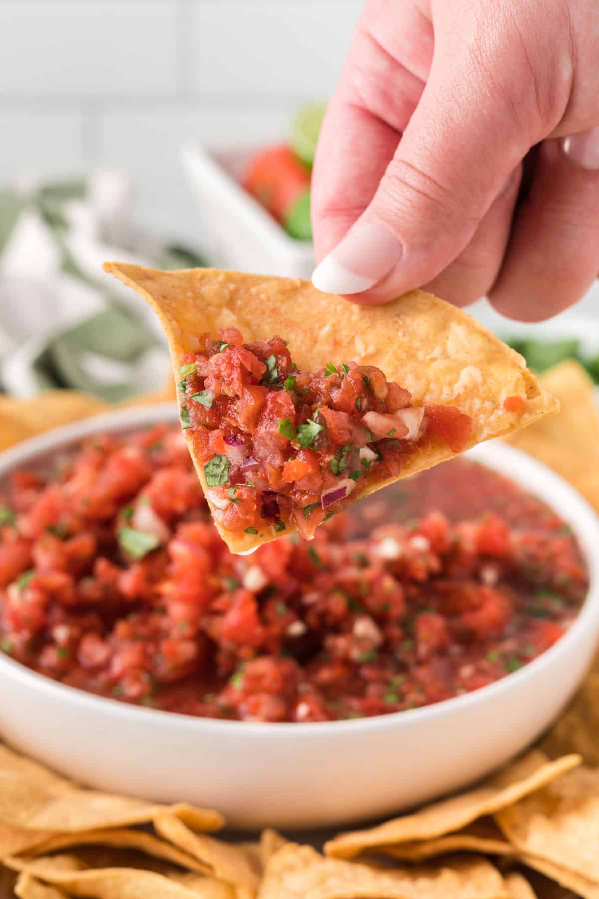 hand holding a chip with salsa