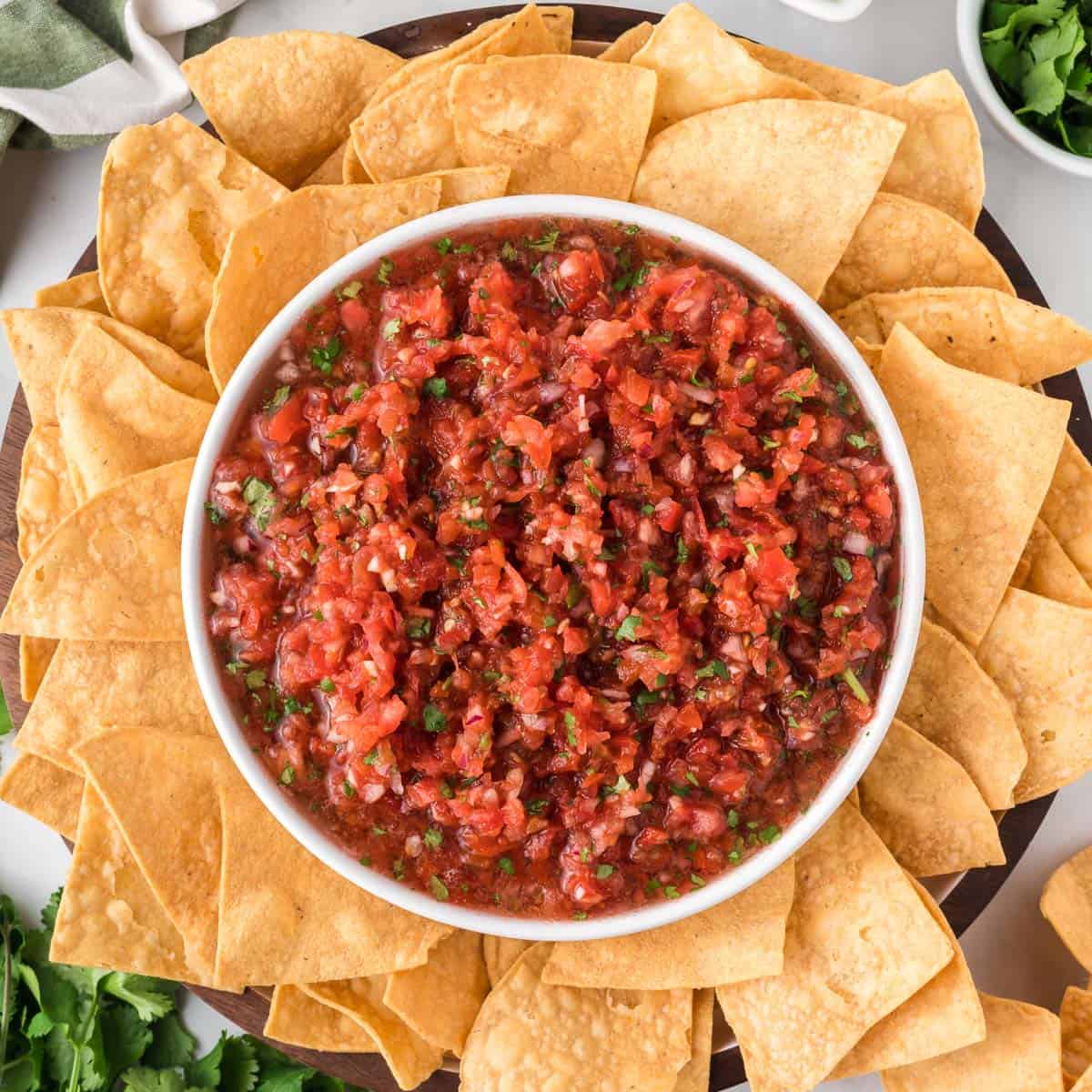 salsa in a bowl surrounded by a platter of tortilla chips