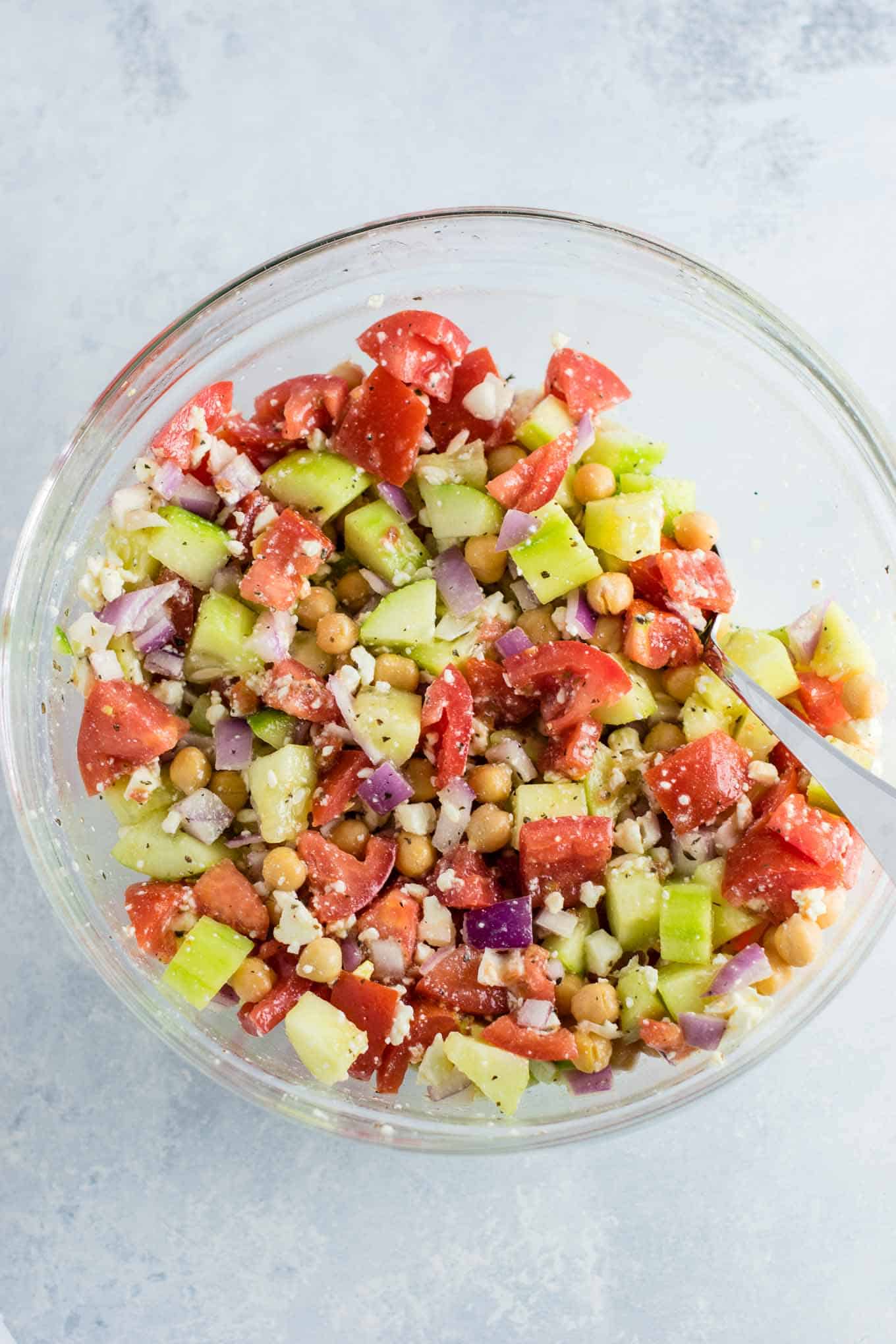 greek chickpea salad mixed together in a bowl with a spoon