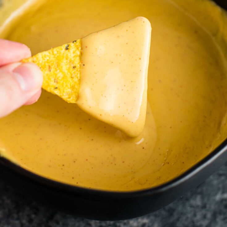 chip being dipped into nacho cheese