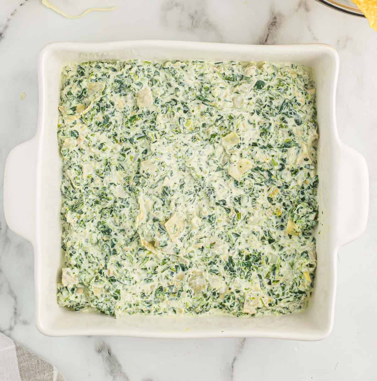 spinach artichoke dip in a white baking dish