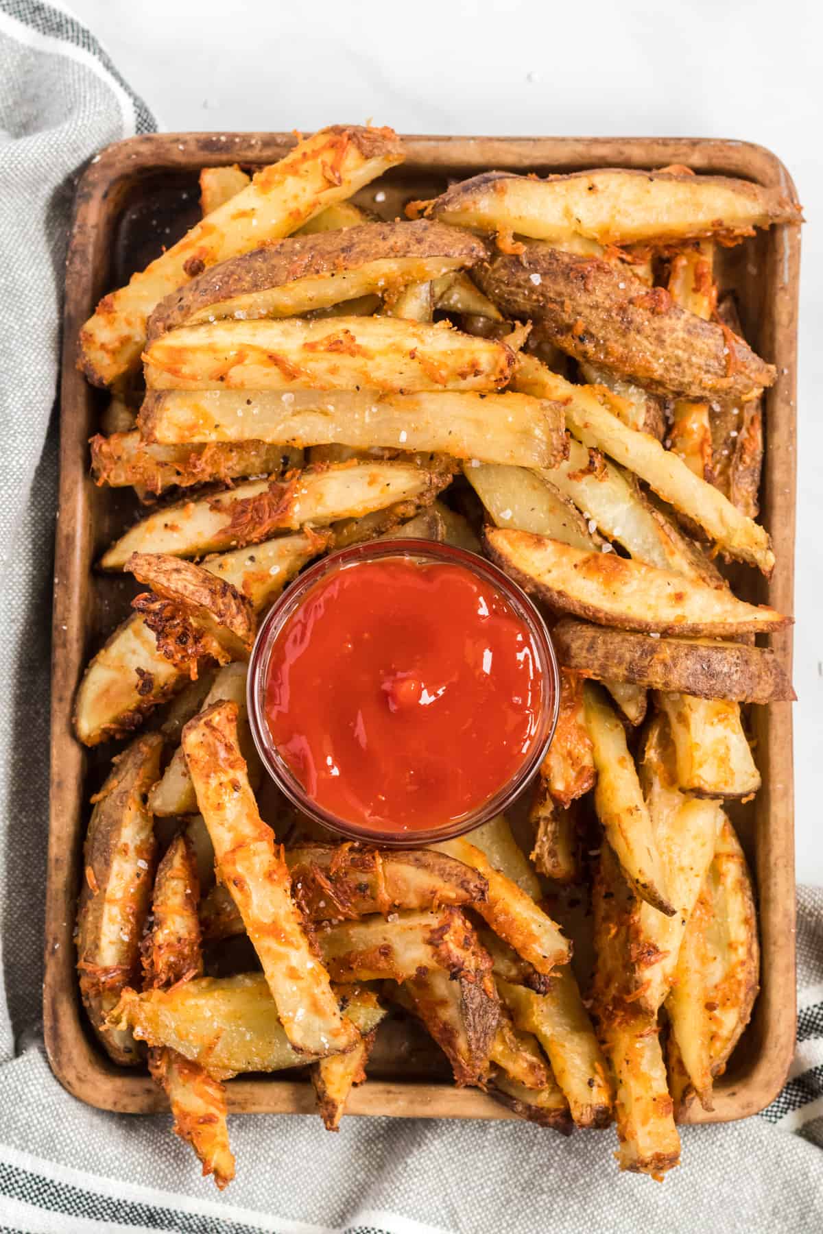 potato wedges on a brown serving tray with ketchup in the middle