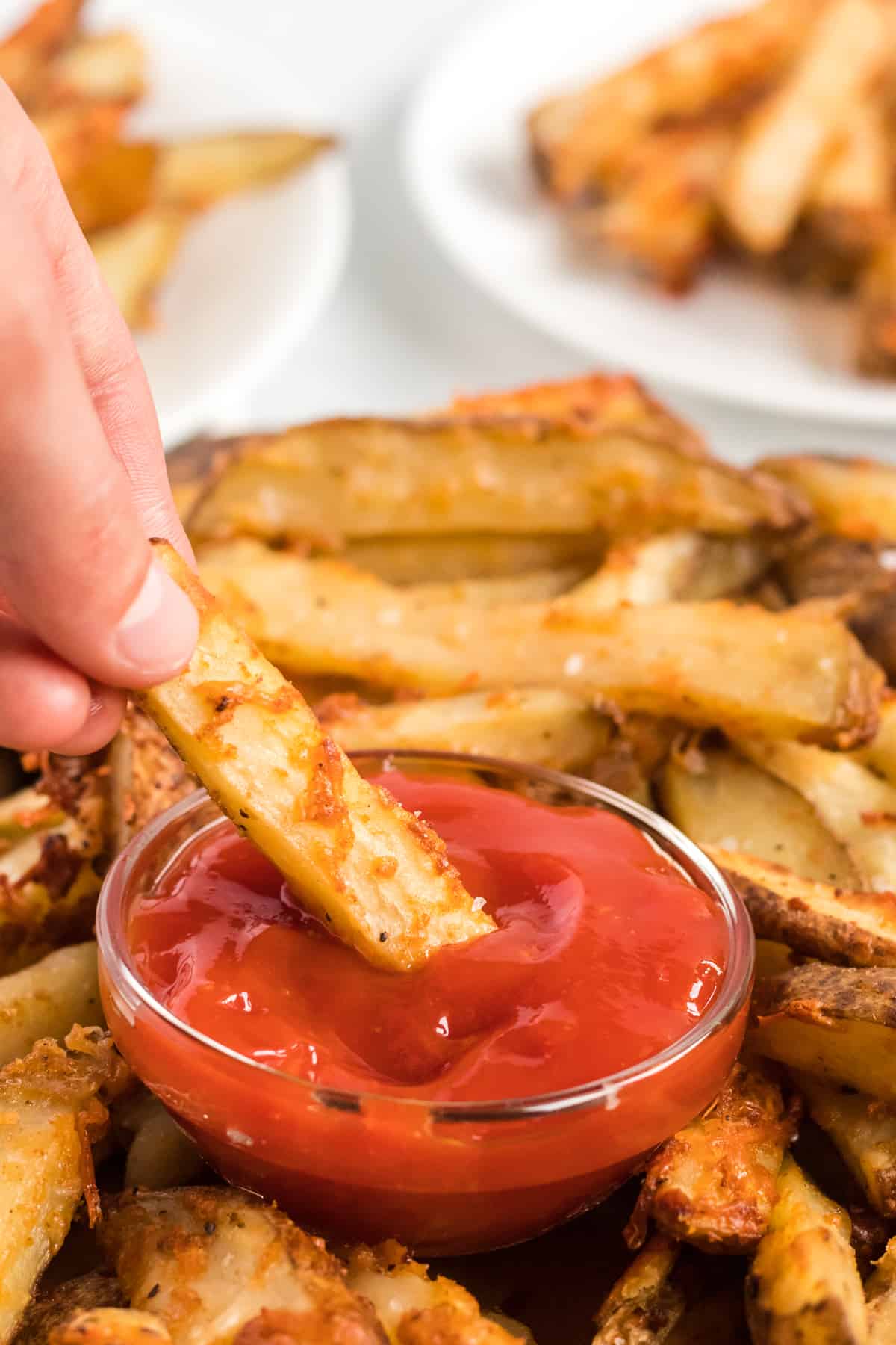 a parmesan crusted potato wedge being dipped in ketchup