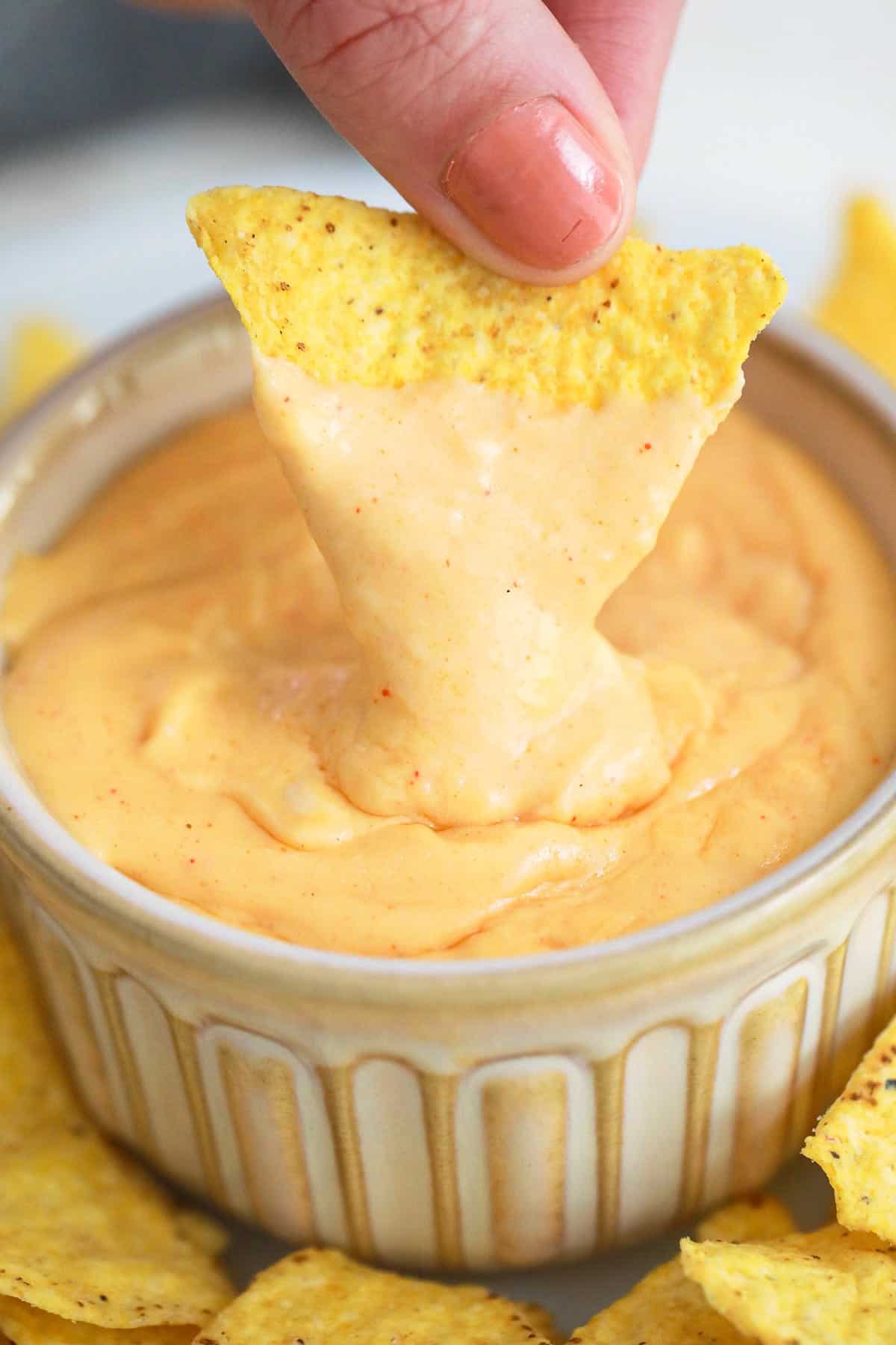 a chip being dipped into nacho cheese