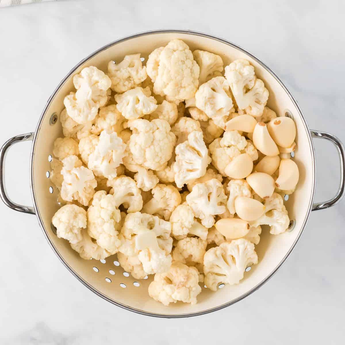 cauliflower florets and garlic cloves in a strainer