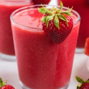 strawberry watermelon smoothie in a clear glass with a strawberry on the rim