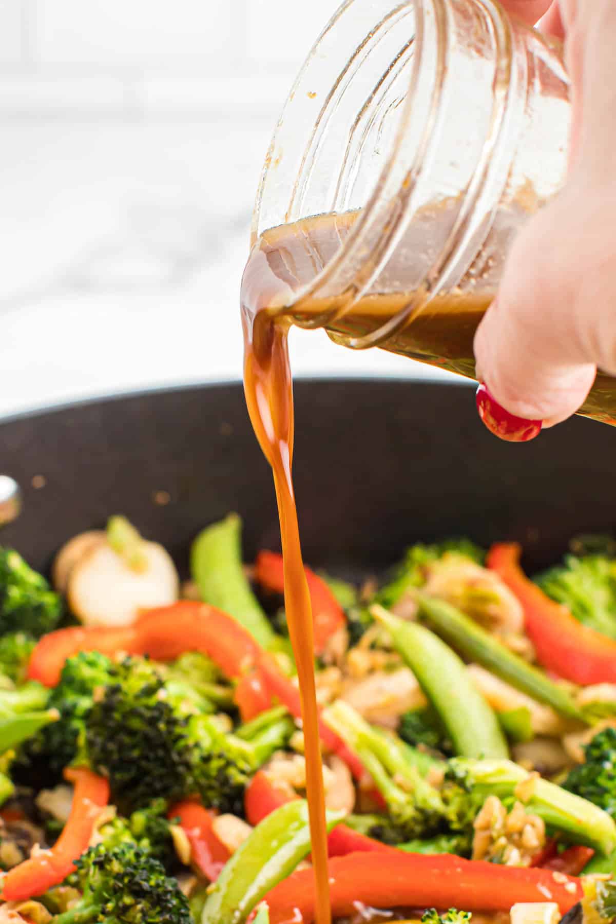 pouring stir fry sauce over vegetables