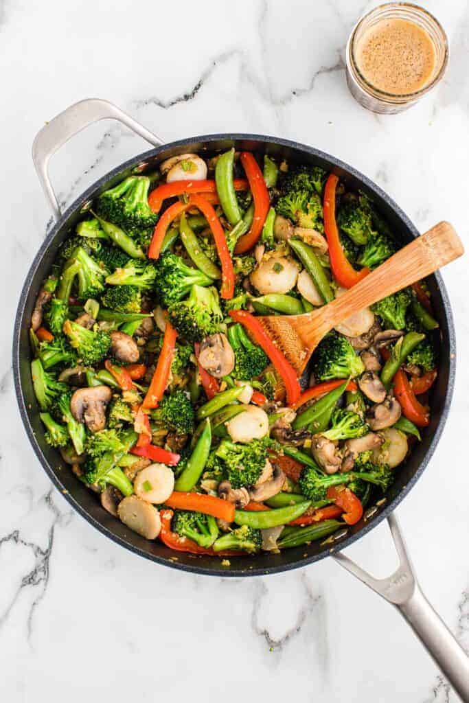 wooden spoon stirring vegetable stir fry