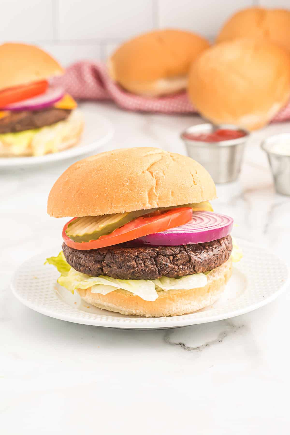 black bean burger on a bun with pickles, tomato, lettuce, and red onion