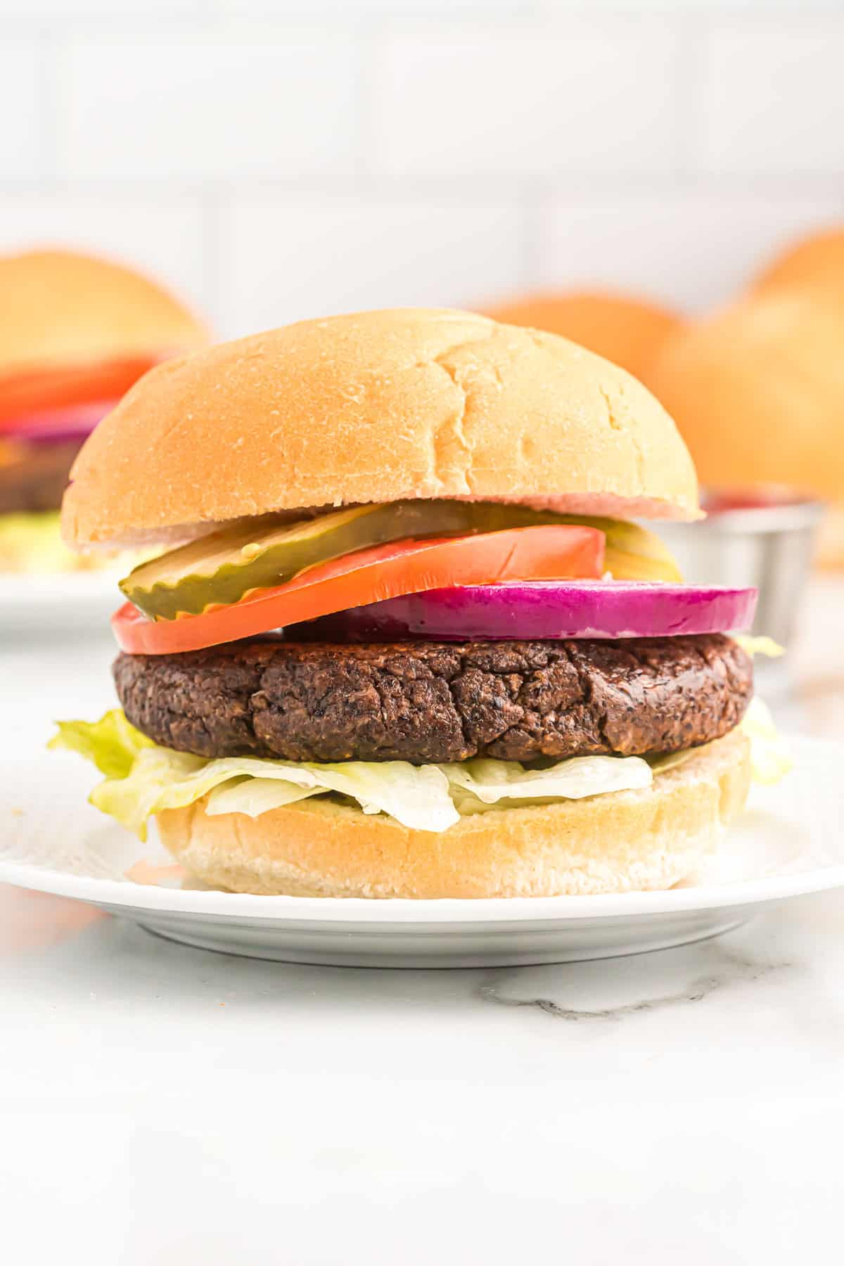 black bean burger on a bun with pickles, tomato, lettuce, and red onion