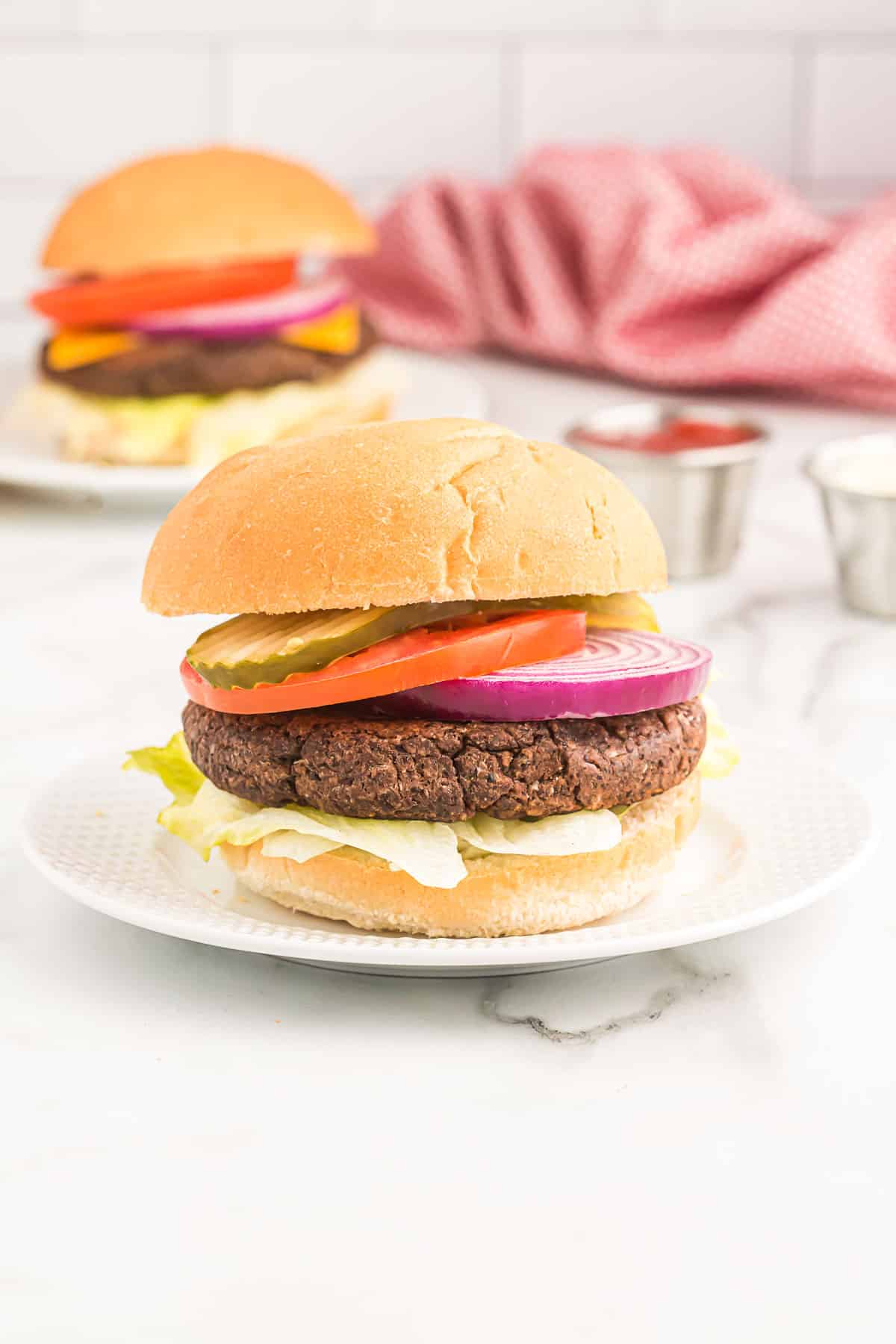 black bean burger on a bun with pickles, tomato, lettuce, and red onion