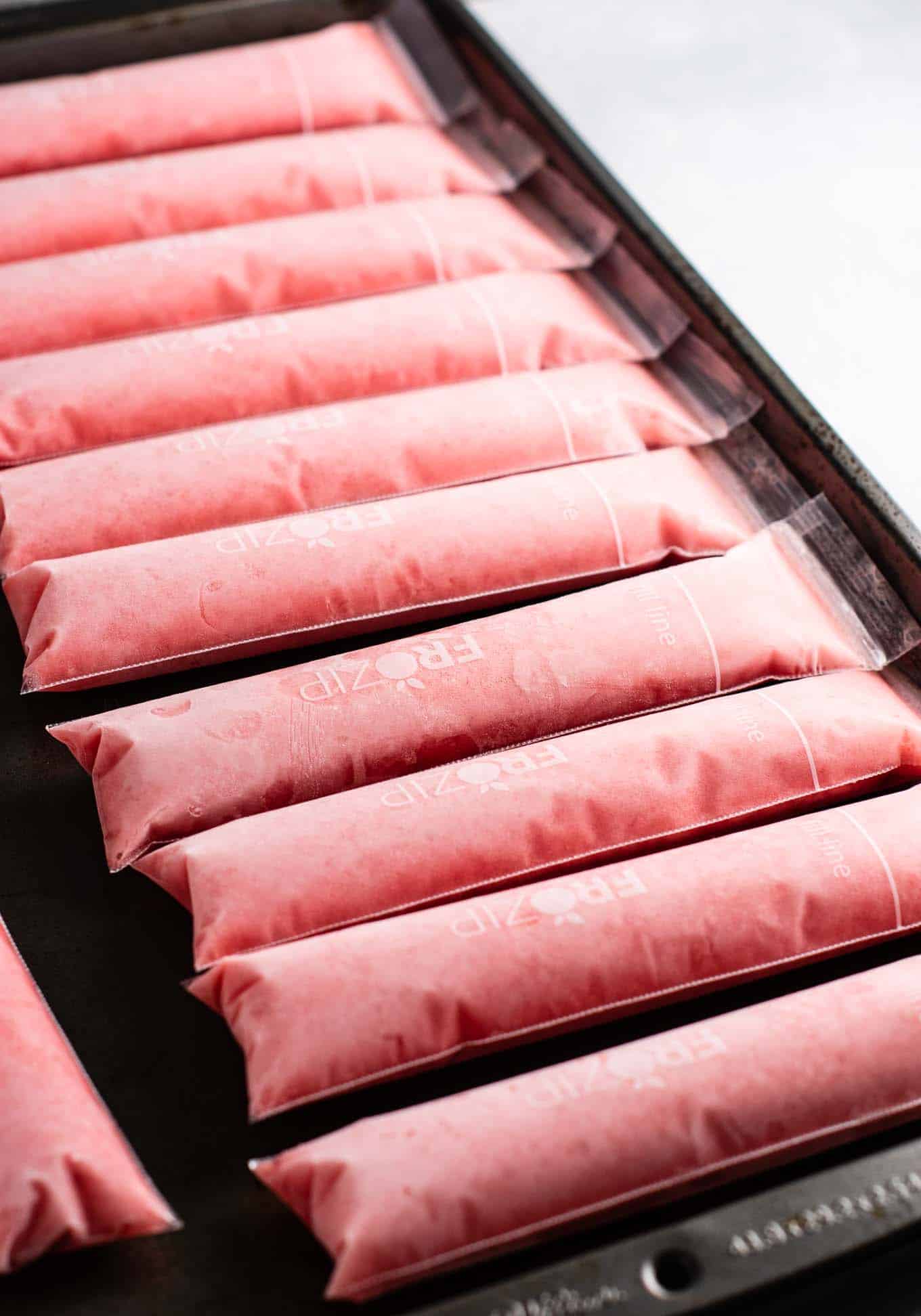 Strawberry pineapple freezer pops – learn how to make popsicles with just frozen fruit, coconut water and maple syrup! #freezerpops #healthy #icepops #popsicles #homemade #healthyrecipe #dessert #healthydessert #strawberrypineapple #summer