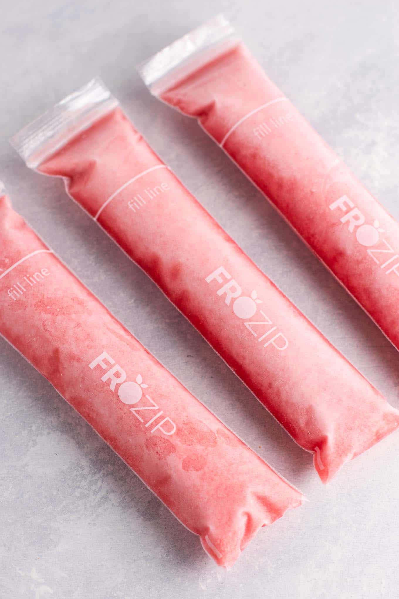 Strawberry pineapple freezer pops – learn how to make popsicles with just frozen fruit, coconut water and maple syrup! #freezerpops #healthy #icepops #popsicles #homemade #healthyrecipe #dessert #healthydessert #strawberrypineapple #summer