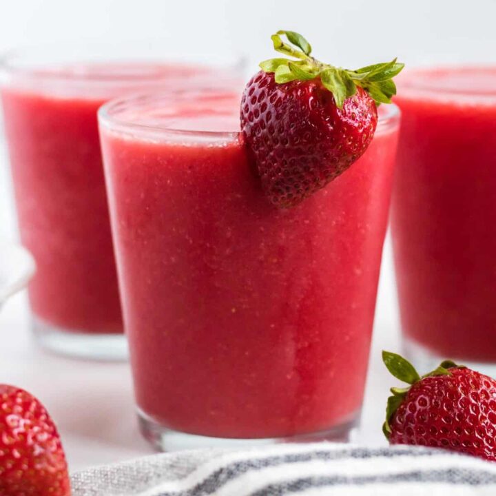 strawberry watermelon smoothie in a glass with a strawberry on the rim