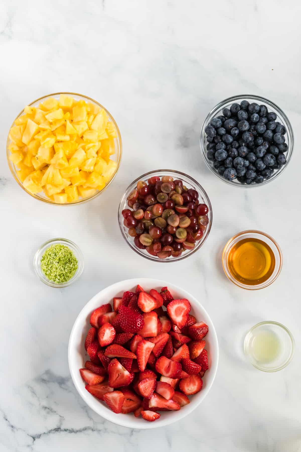 fruit salad ingredients in separate glass bowls