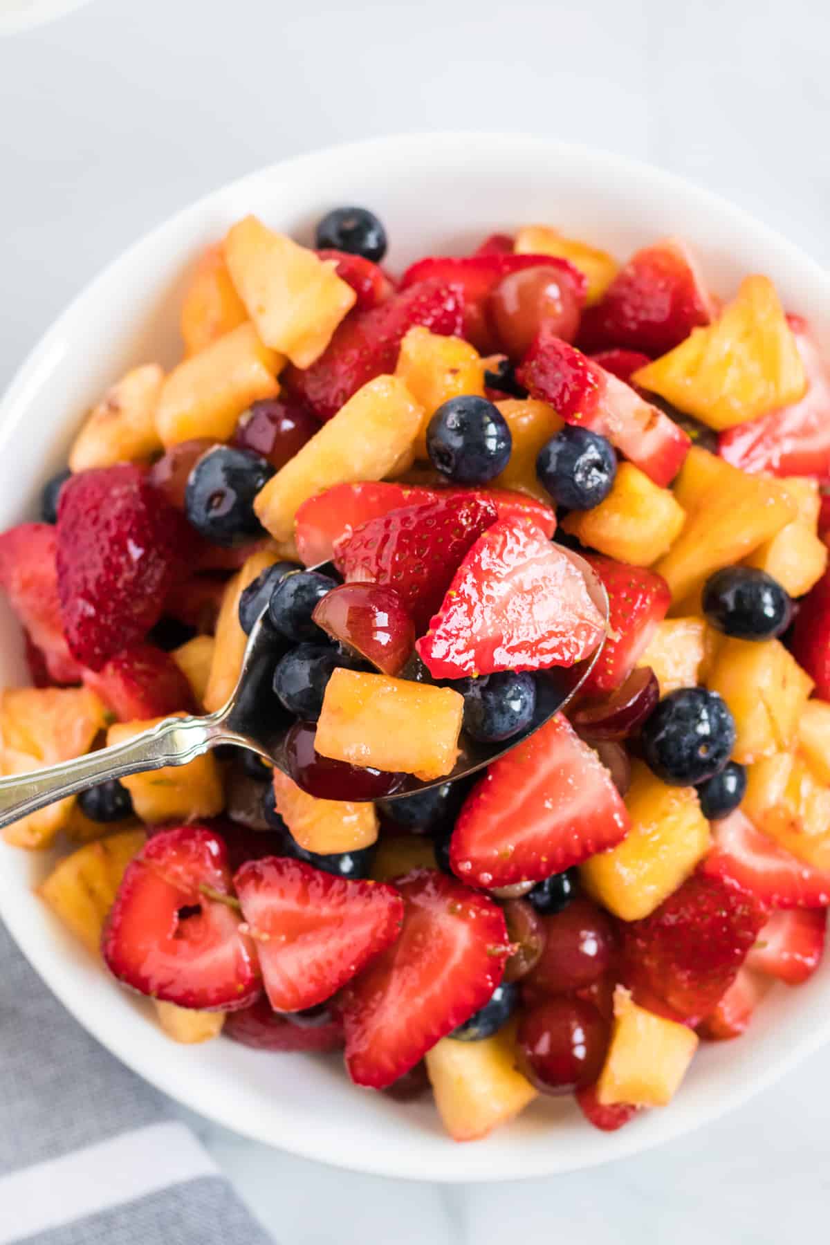 spoon taking a serving of fruit salad from the dish