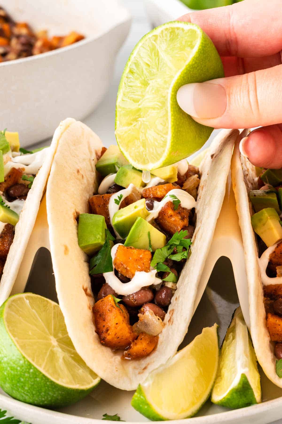 squeezing fresh lime juice onto a sweet potato taco