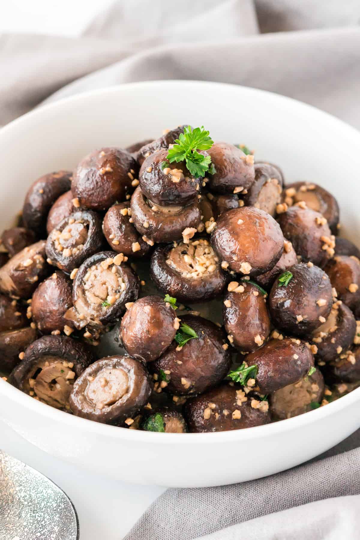 garlic butter mushrooms in a white bowl with parsley on top