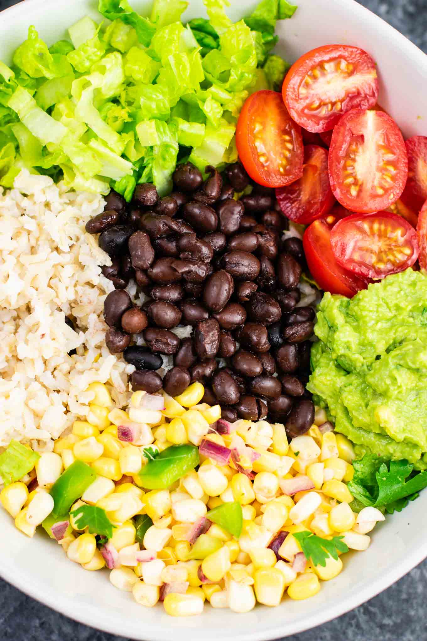 Vegan burrito bowl recipe with homemade fresh corn salsa and guacamole. Better than chipotle and so fresh and delicious! #vegan #burritobowl #meatless #chipotle #mexican #dinner #vegetarian #mealprep #dairyfree #guacamole #cornsalsa