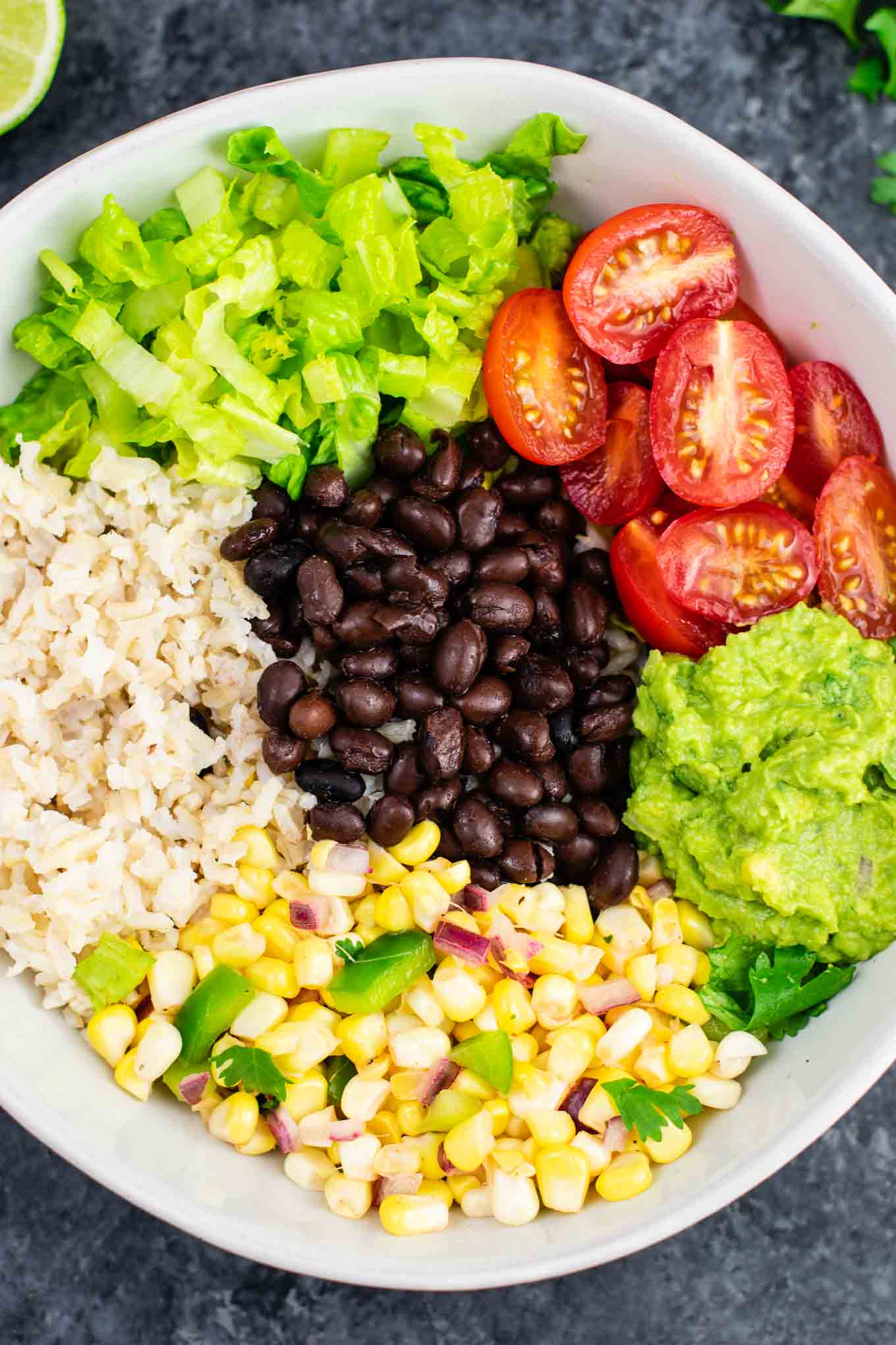 Vegan burrito bowl recipe with homemade fresh corn salsa and guacamole. Better than chipotle and so fresh and delicious! #vegan #burritobowl #meatless #chipotle #mexican #dinner #vegetarian #mealprep #dairyfree #guacamole #cornsalsa