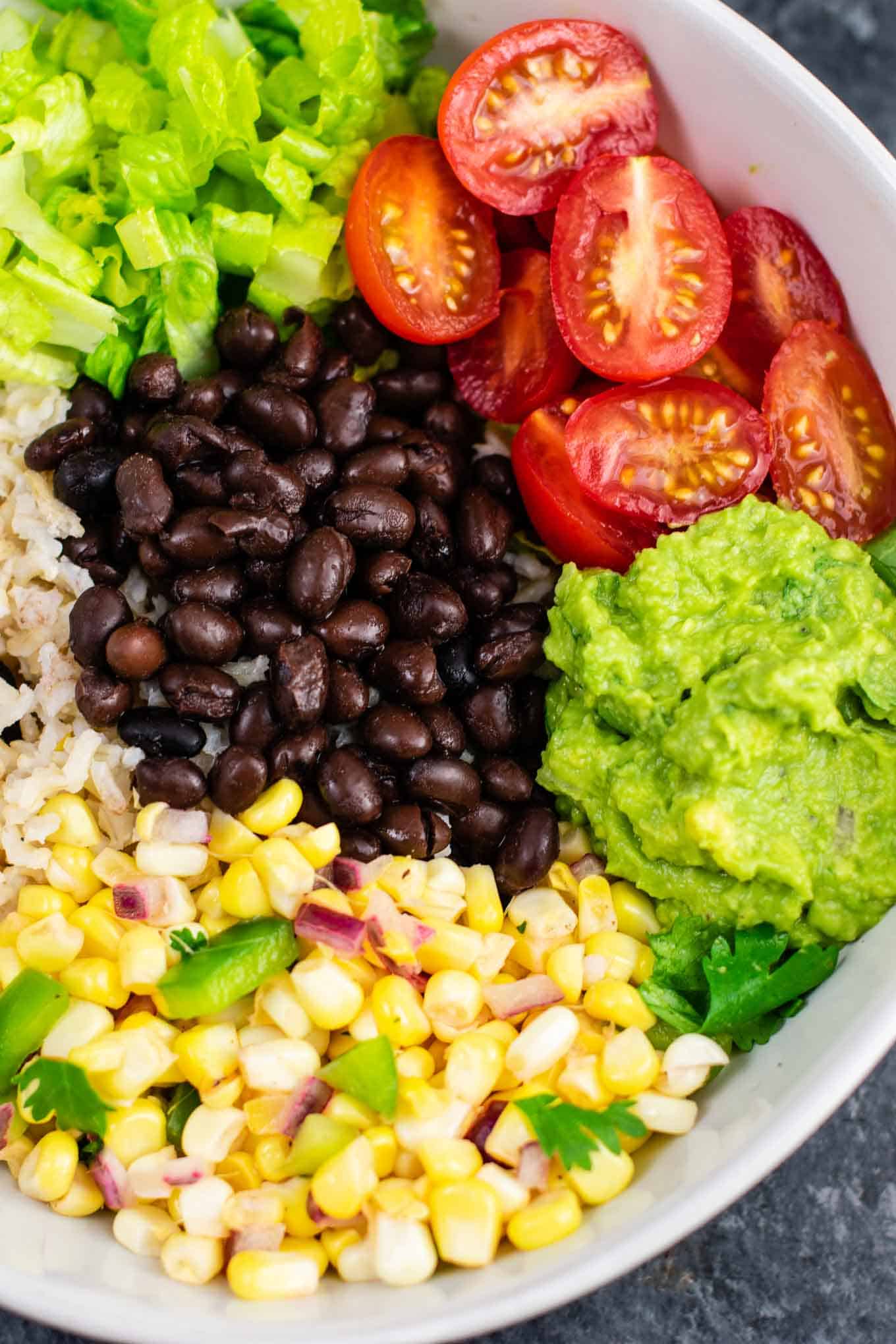 Vegan burrito bowl recipe with homemade fresh corn salsa and guacamole. Better than chipotle and so fresh and delicious! #vegan #burritobowl #meatless #chipotle #mexican #dinner #vegetarian #mealprep #dairyfree #guacamole #cornsalsa