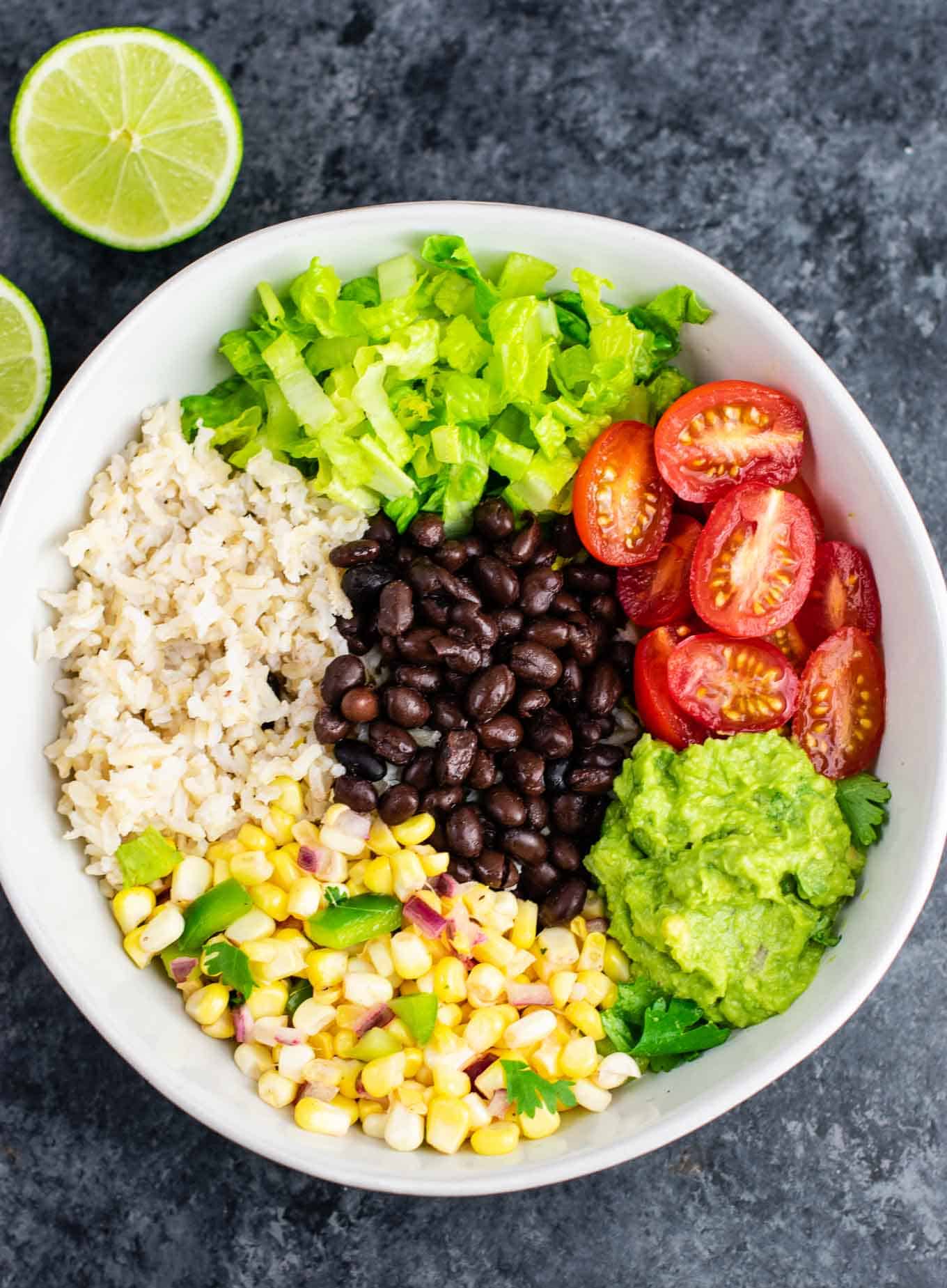 Vegan burrito bowl recipe with homemade fresh corn salsa and guacamole. Better than chipotle and so fresh and delicious! #vegan #burritobowl #meatless #chipotle #mexican #dinner #vegetarian #mealprep #dairyfree #guacamole #cornsalsa