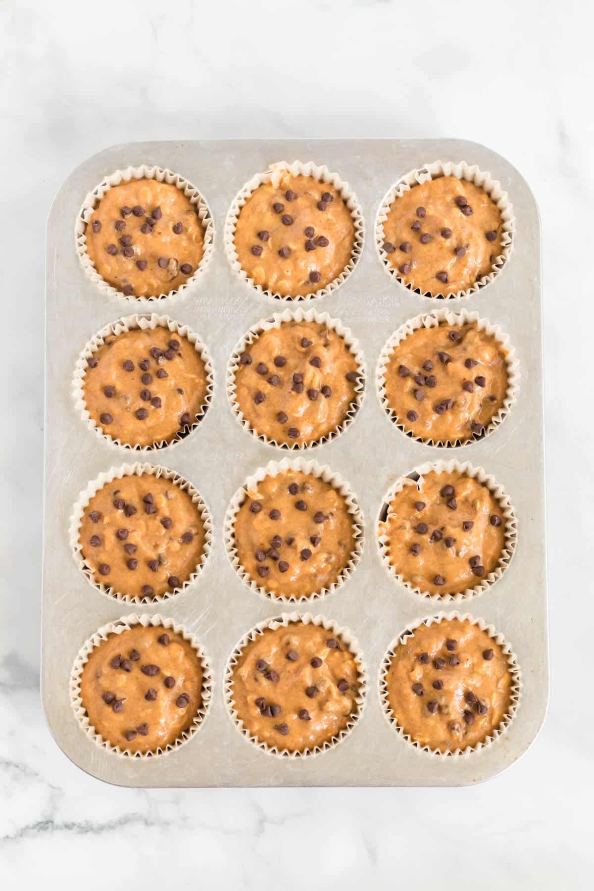 pumpkin muffin batter in lined muffin tins