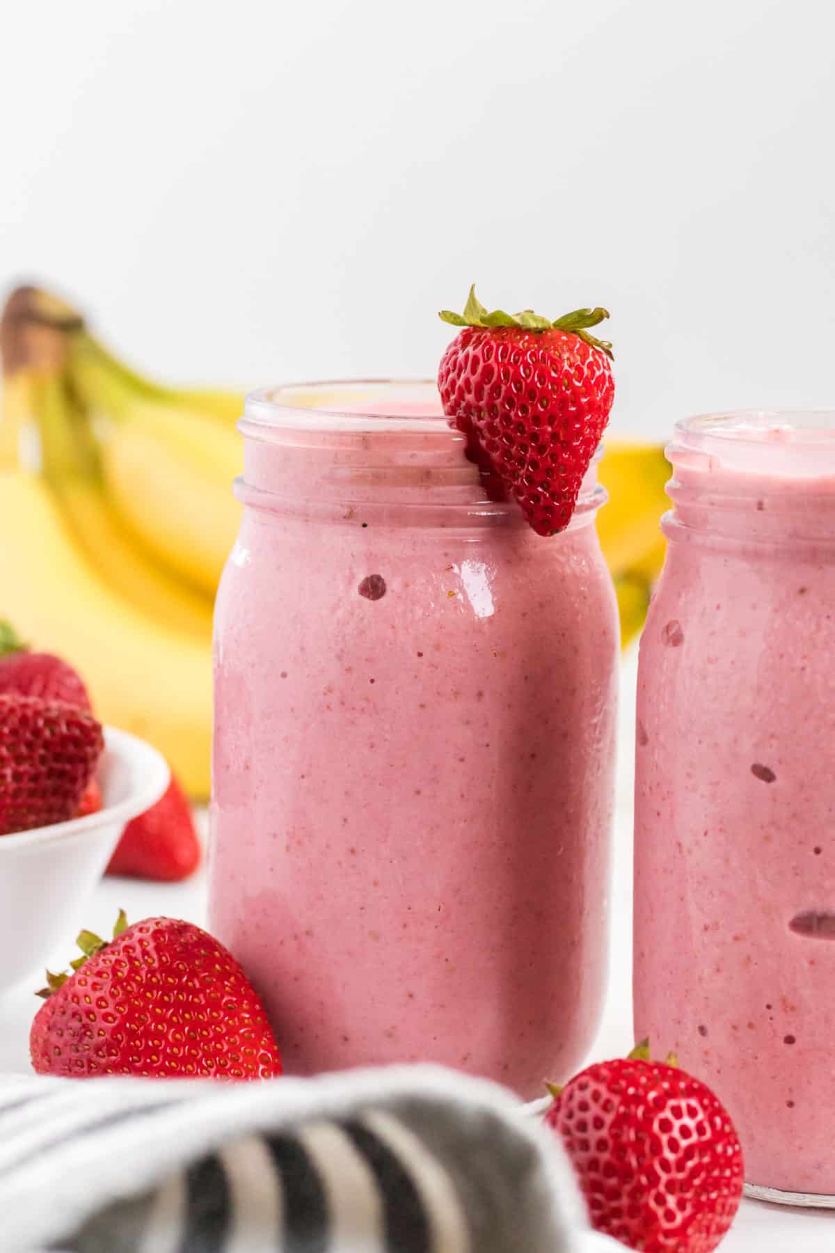 strawberry banana smoothie in a mason jar with a strawberry on the rim