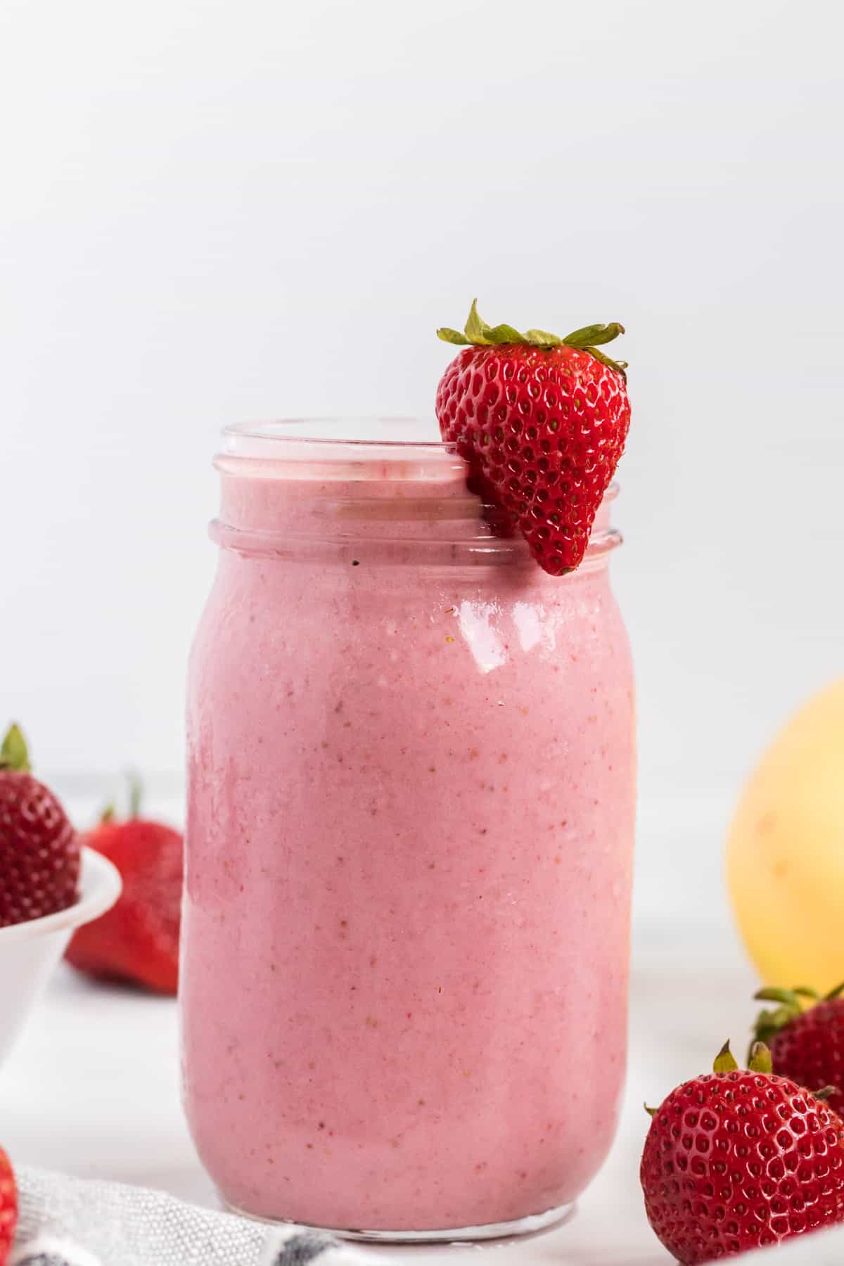 strawberry banana smoothie in a mason jar with a strawberry on the rim