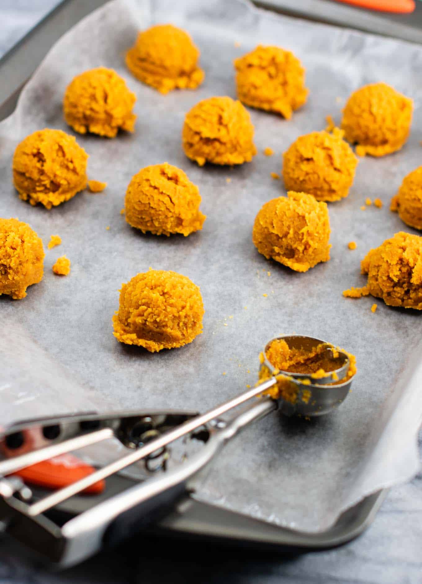 pumpkin truffle scoops on a wax paper lined baking sheet