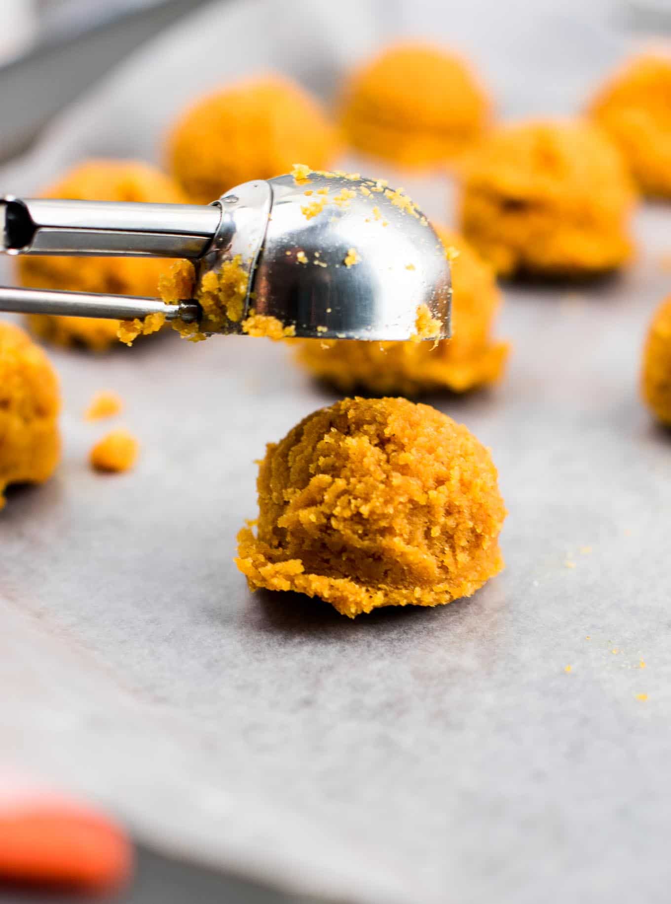 using a cookie scoop to drop truffle dough on to a baking sheet