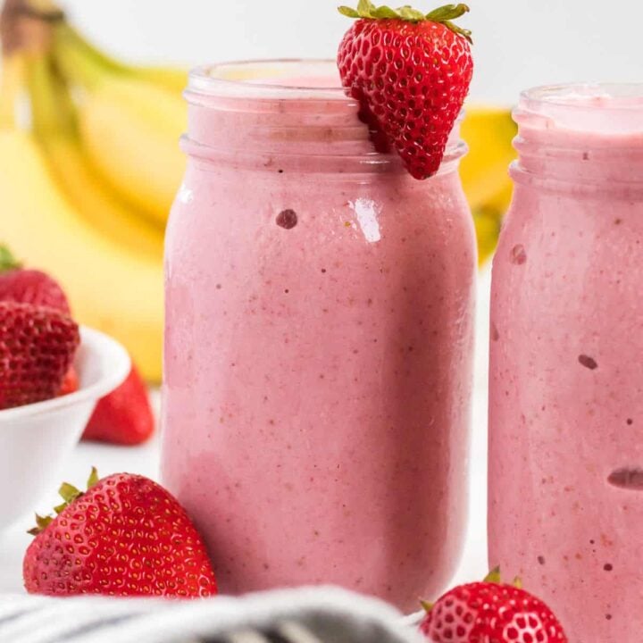 strawberry banana smoothie in a mason jar with a strawberry on the rim