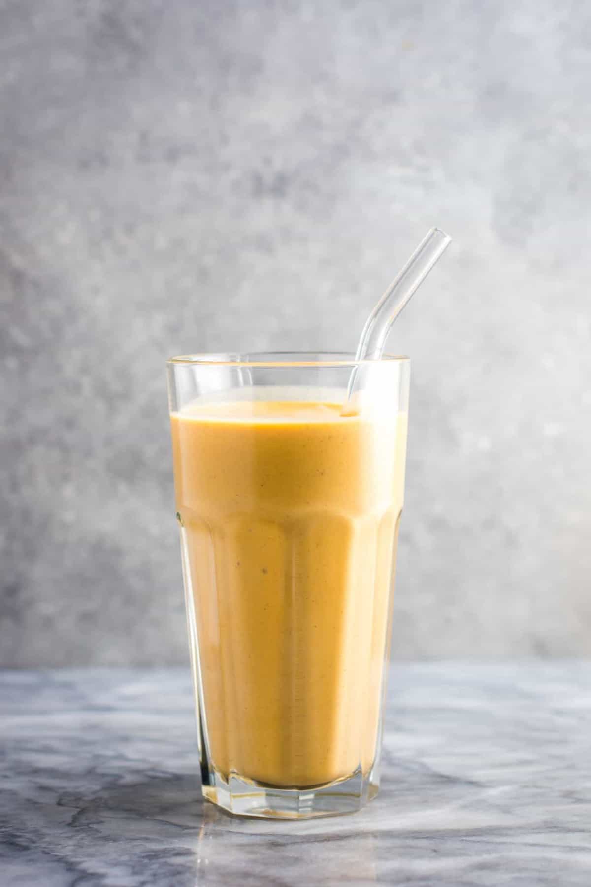 Sweet potato smoothie in a glass with a glass straw