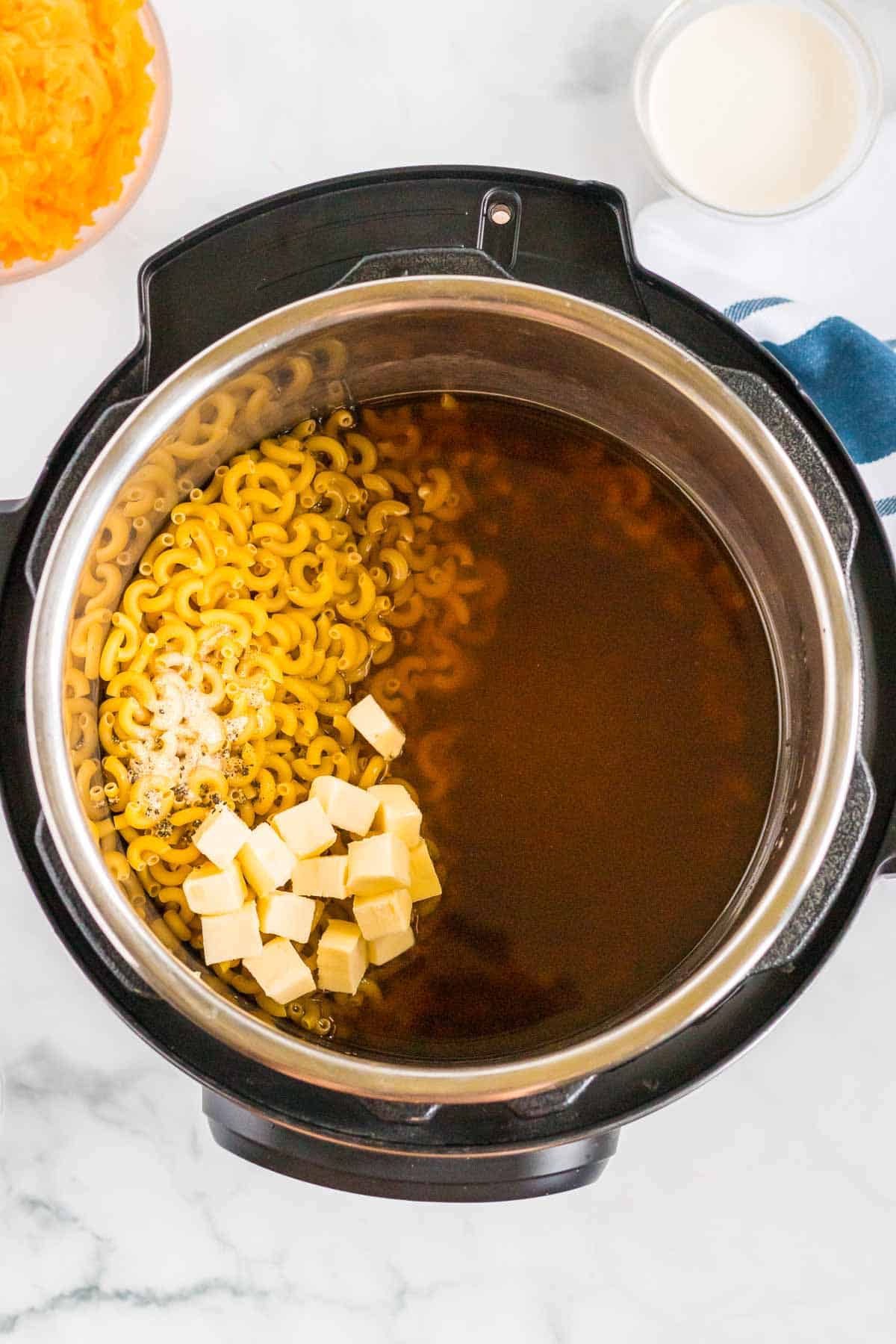 vegetable broth, macaroni noodles, and butter inside an instant pot