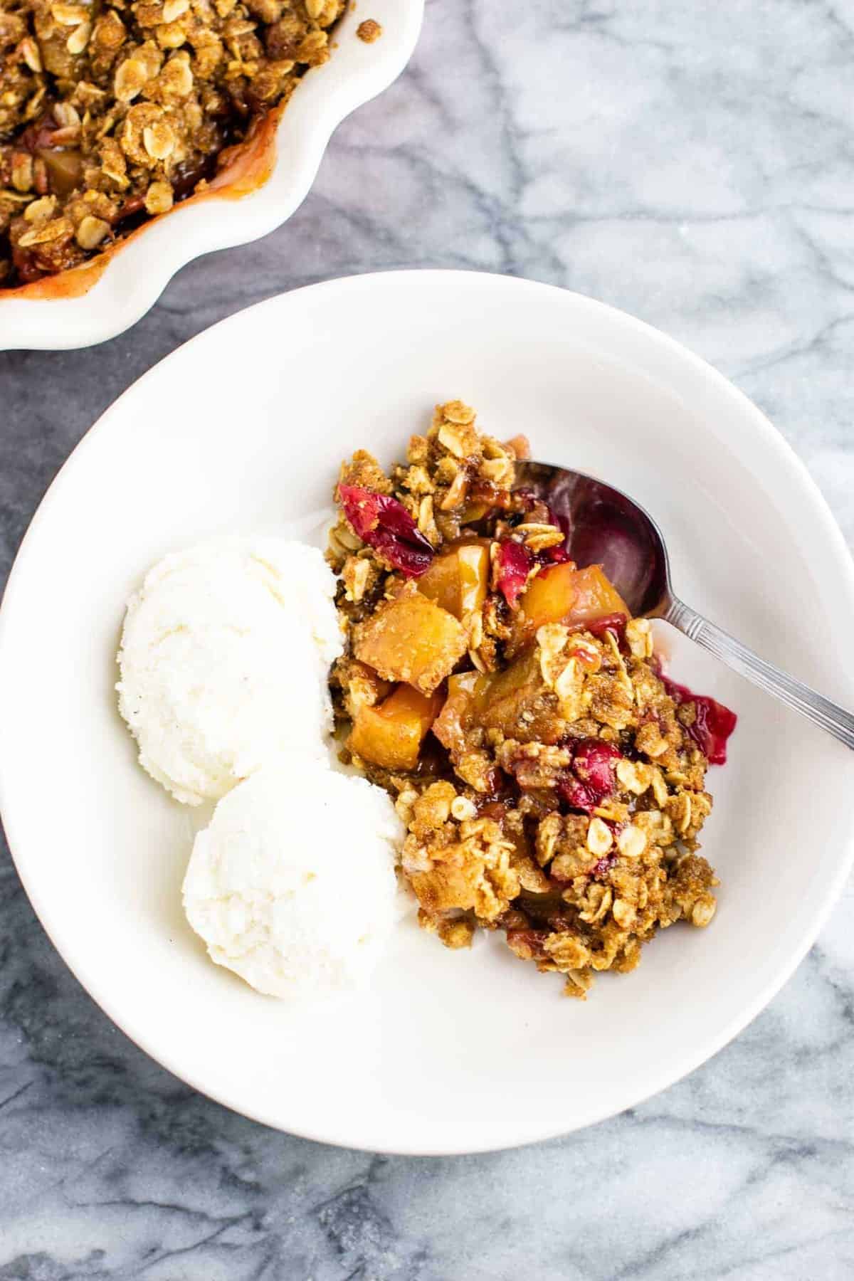cranberry apple crisp in a bowl with ice cream