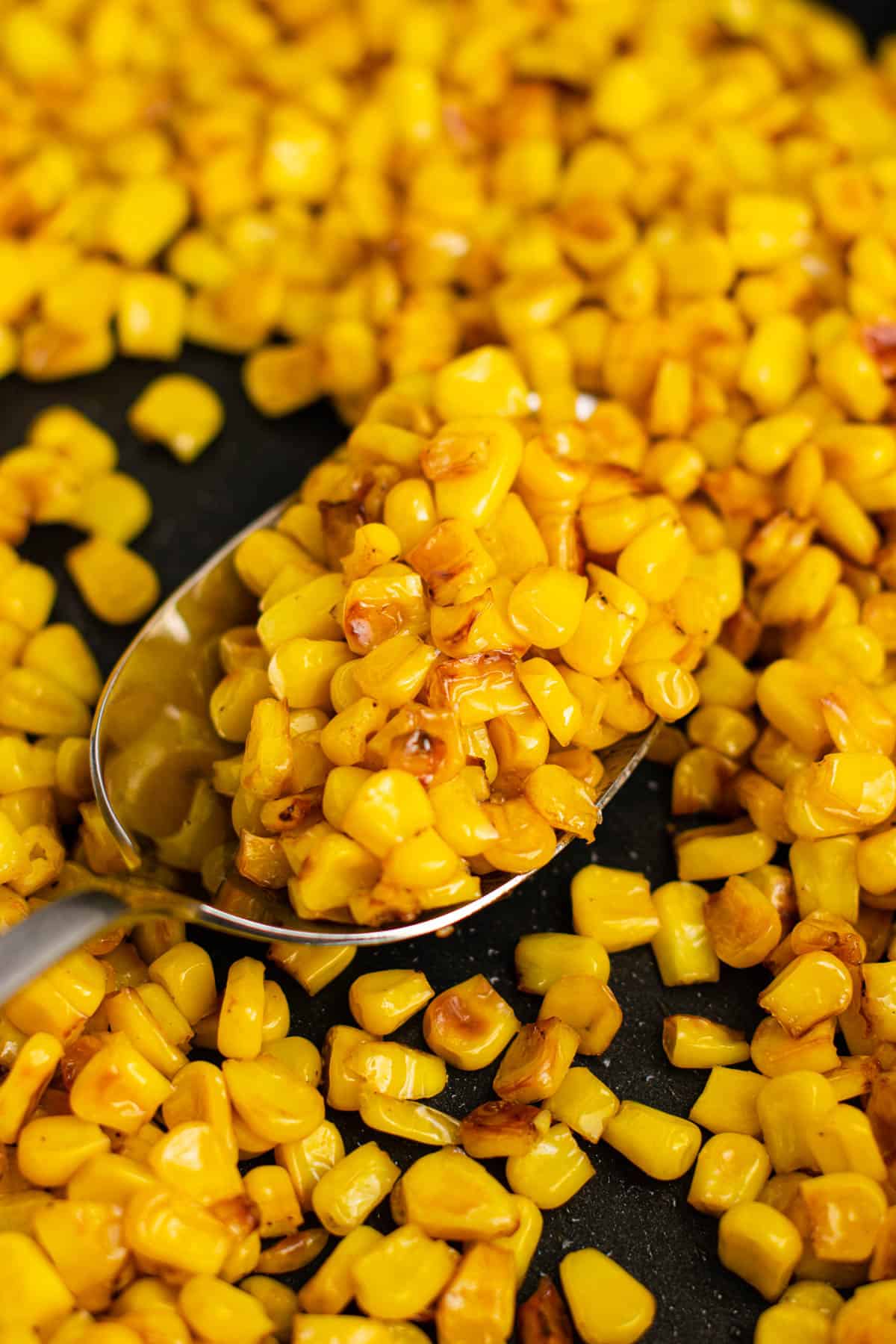taking a spoonful of corn from the skillet