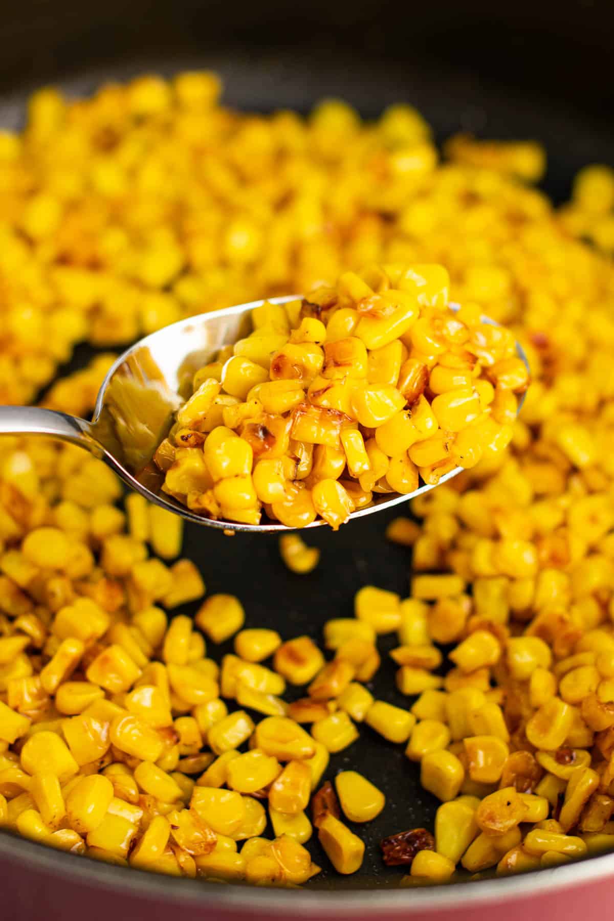 taking a spoonful of corn from the skillet