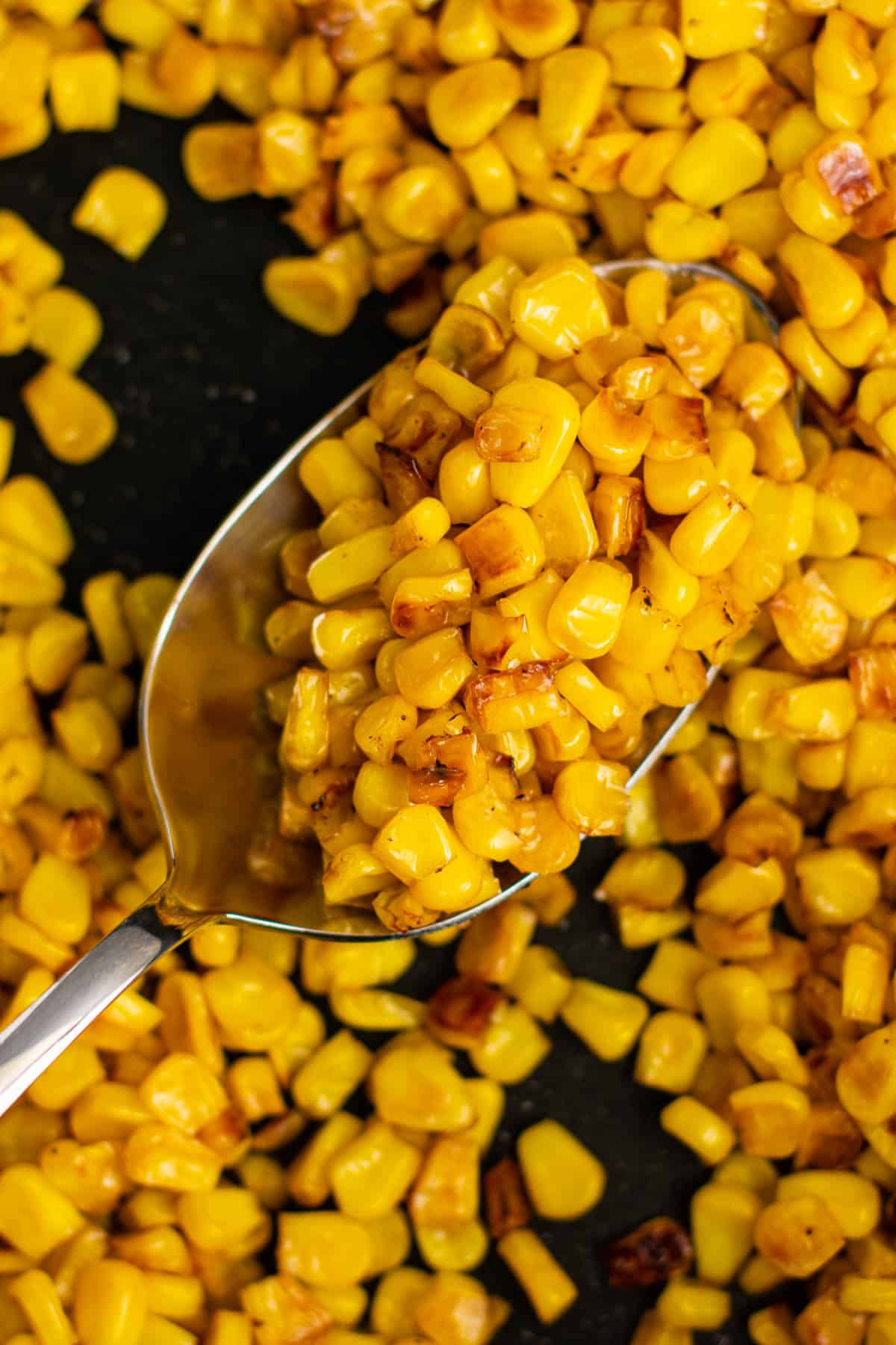 taking a spoonful of corn from the skillet