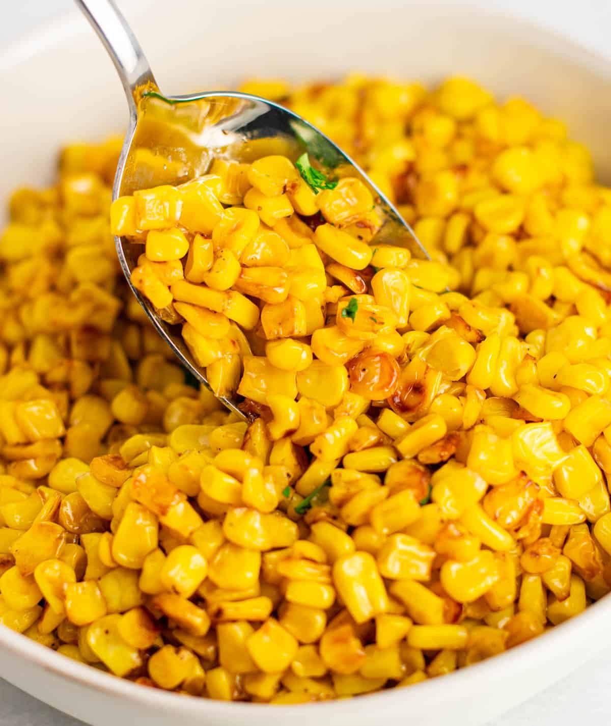 taking a spoonful of corn from the skillet