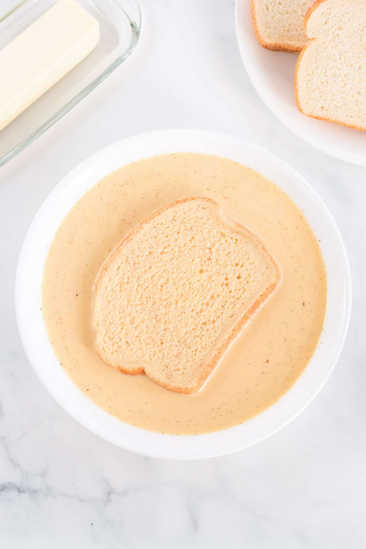 dipping a piece of toast in french toast batter