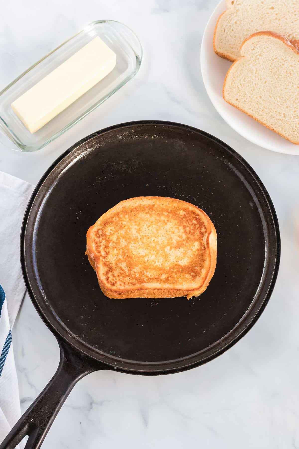 cooking the french toast in a cast iron skillet