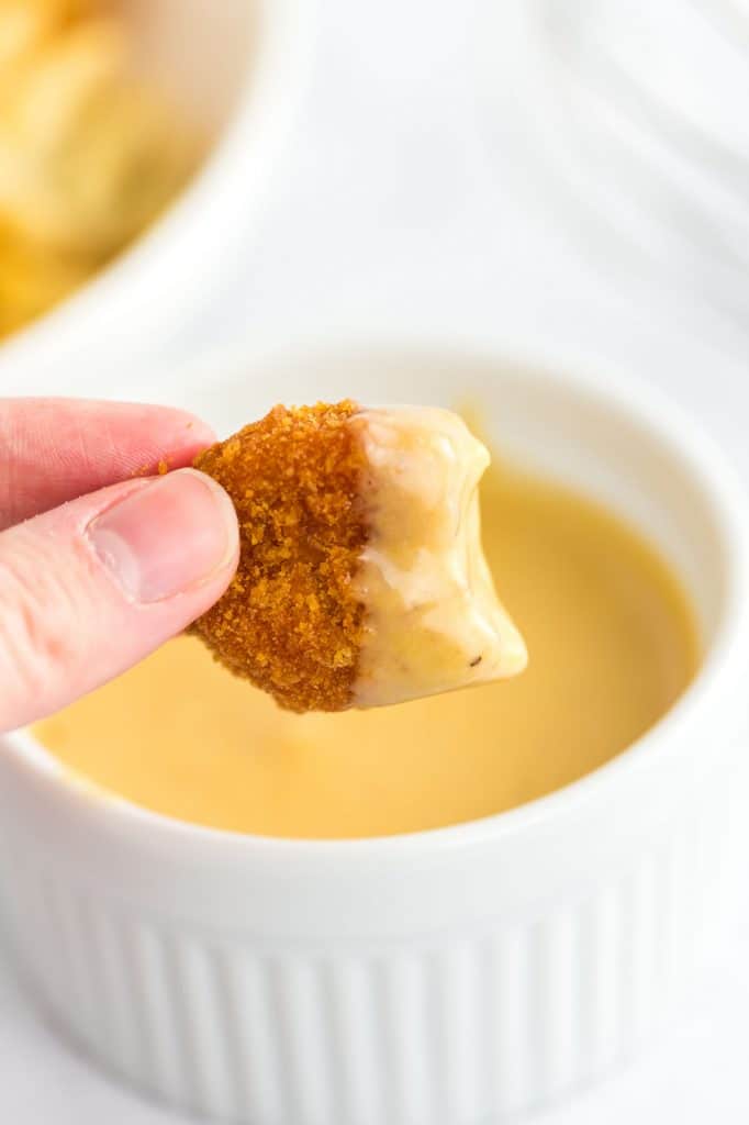 chicken nugget dipped in chick fil a sauce with a bite taken out