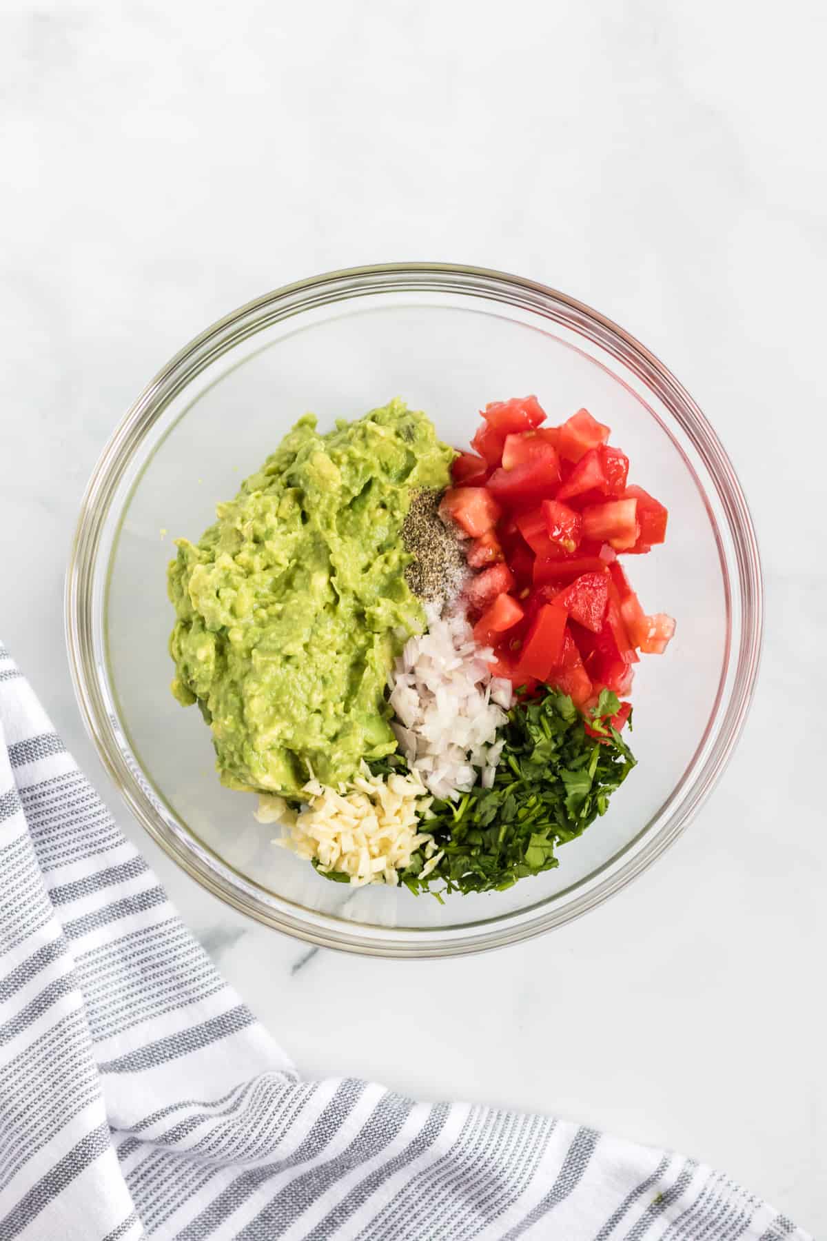 mashed avocado, shallot, garlic, cilantro, and diced roma tomatoes in a bowl