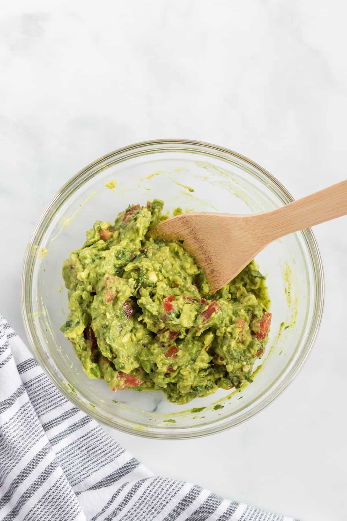 guacamole mixed together with a wooden spoon